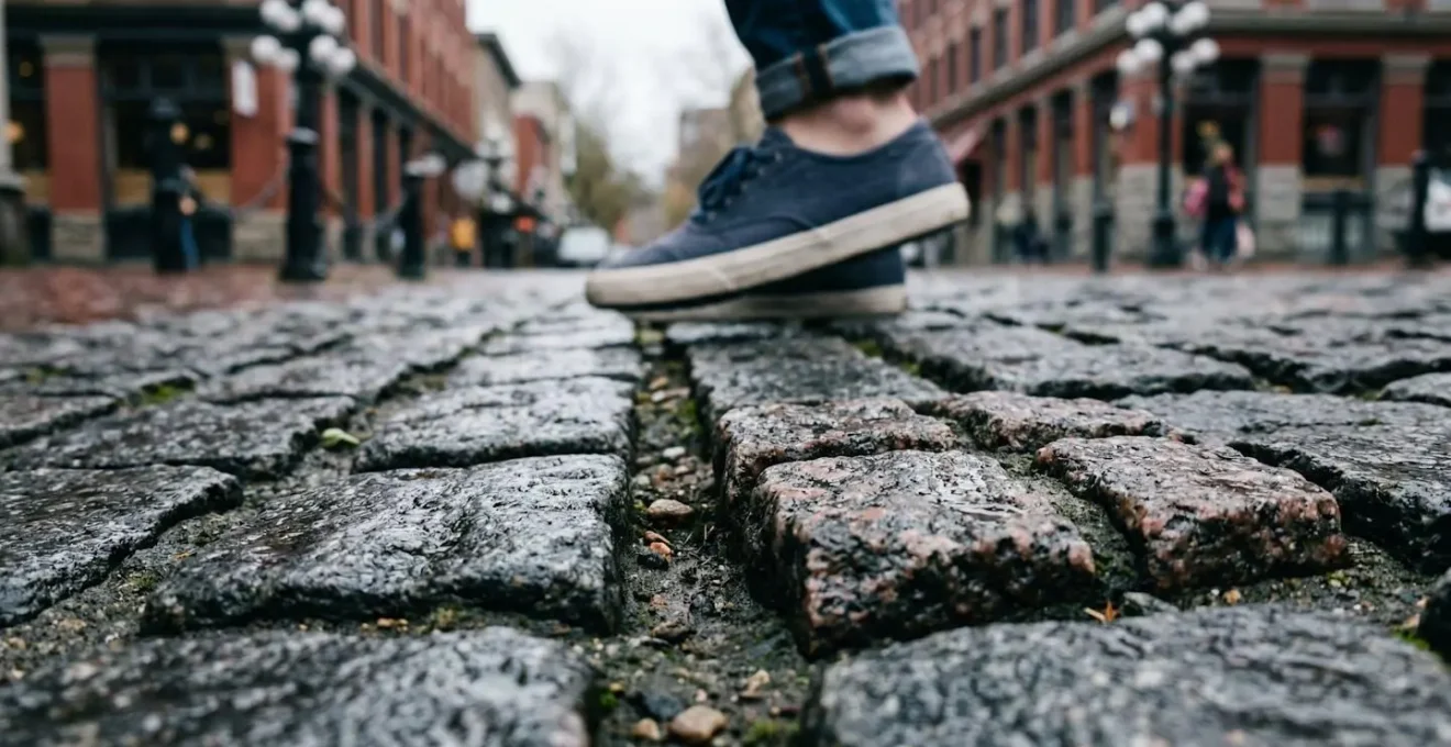 Close-up view of historic granite cobblestones on Water Street in Gastown Vancouver with pedestrian wearing practical flat footwear