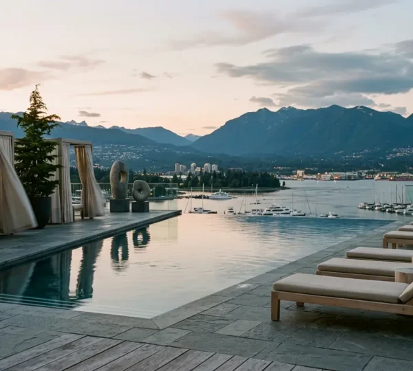 Tranquil luxury hotel spa setting with infinity pool overlooking Vancouver harbour and coastal mountains at golden hour