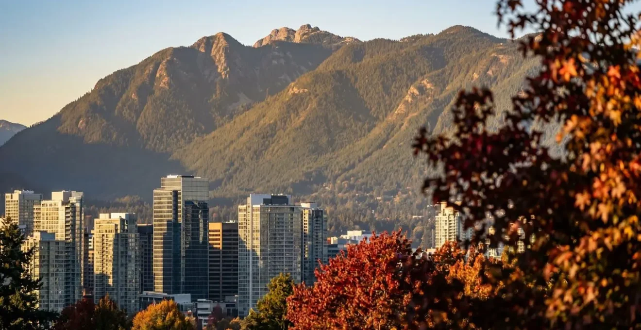Compressed telephoto view of Vancouver skyline framed by North Shore mountains and autumn foliage