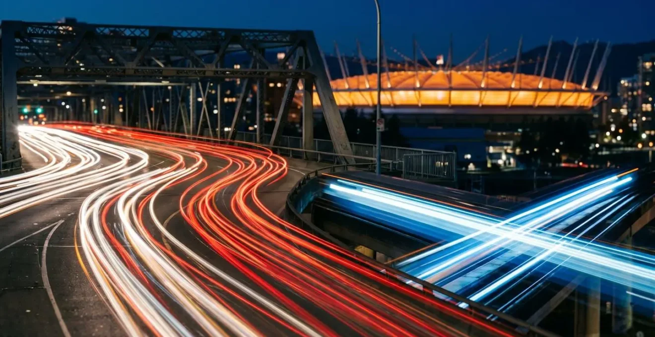 Long exposure photograph of S-curve light trails from Cambie Street Bridge with SkyTrain passing underneath at night