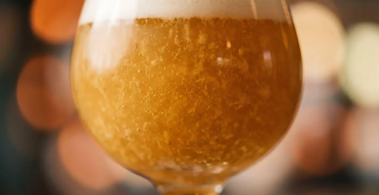 Extreme close-up of hazy IPA beer showcasing thick golden texture with suspended yeast and hop particles
