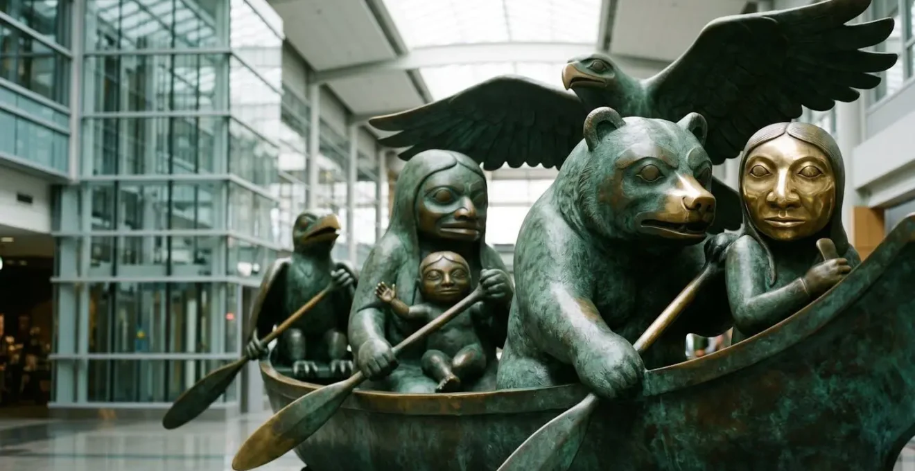 Bronze sculpture detail showing mythological Haida figures crowded together in ceremonial canoe