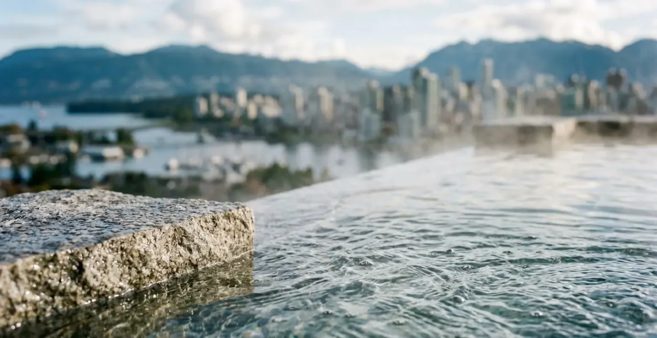 Outdoor spa hydrotherapy pool with steam rising against Vancouver harbour and mountain panorama